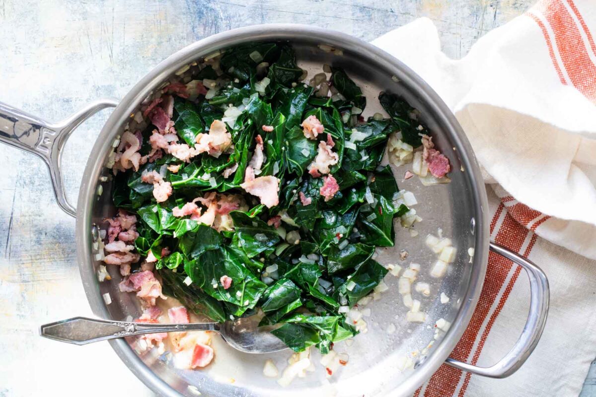A skillet full of collard greens with bacon.