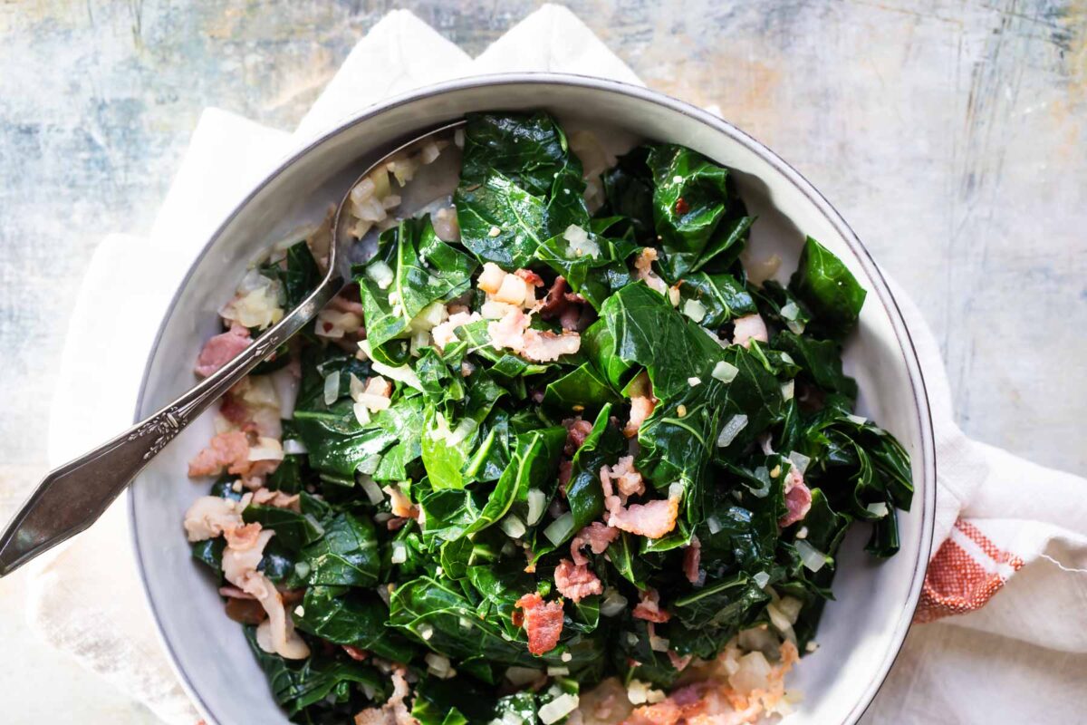 A bowl of collard greens with bacon and onions.
