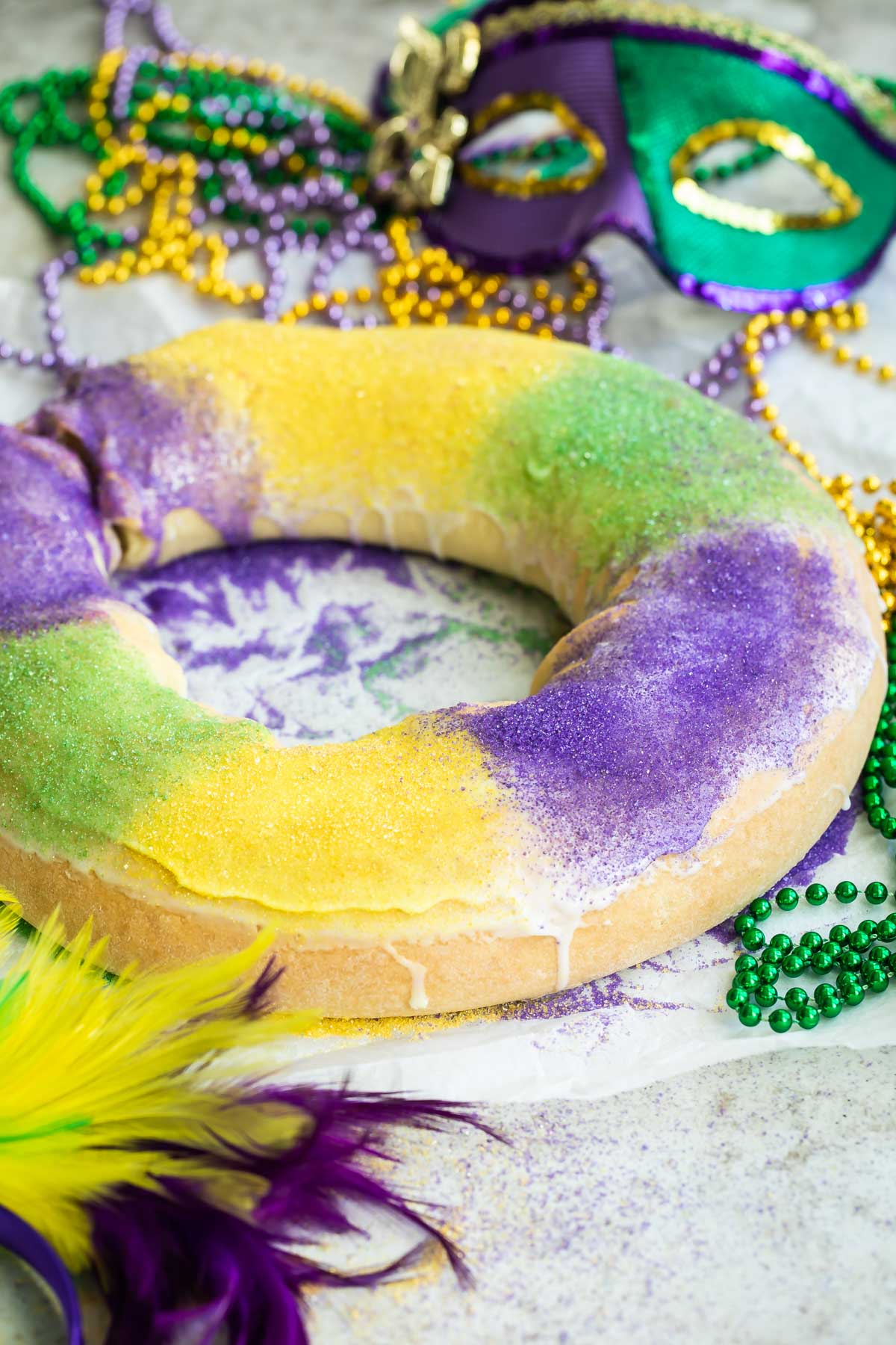A king cake surrounded Mardi Gras decorations.