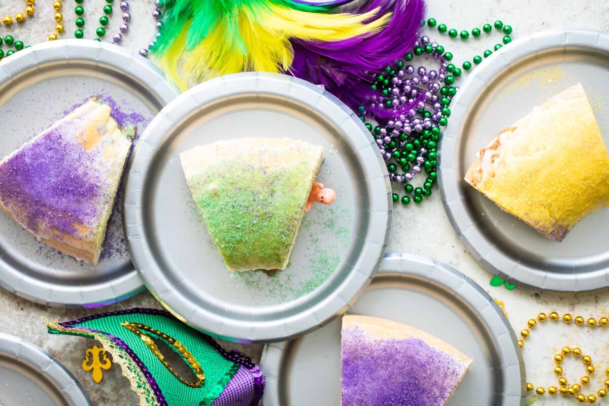 A slice of king cake with a plastic baby popping out on a silver plate.