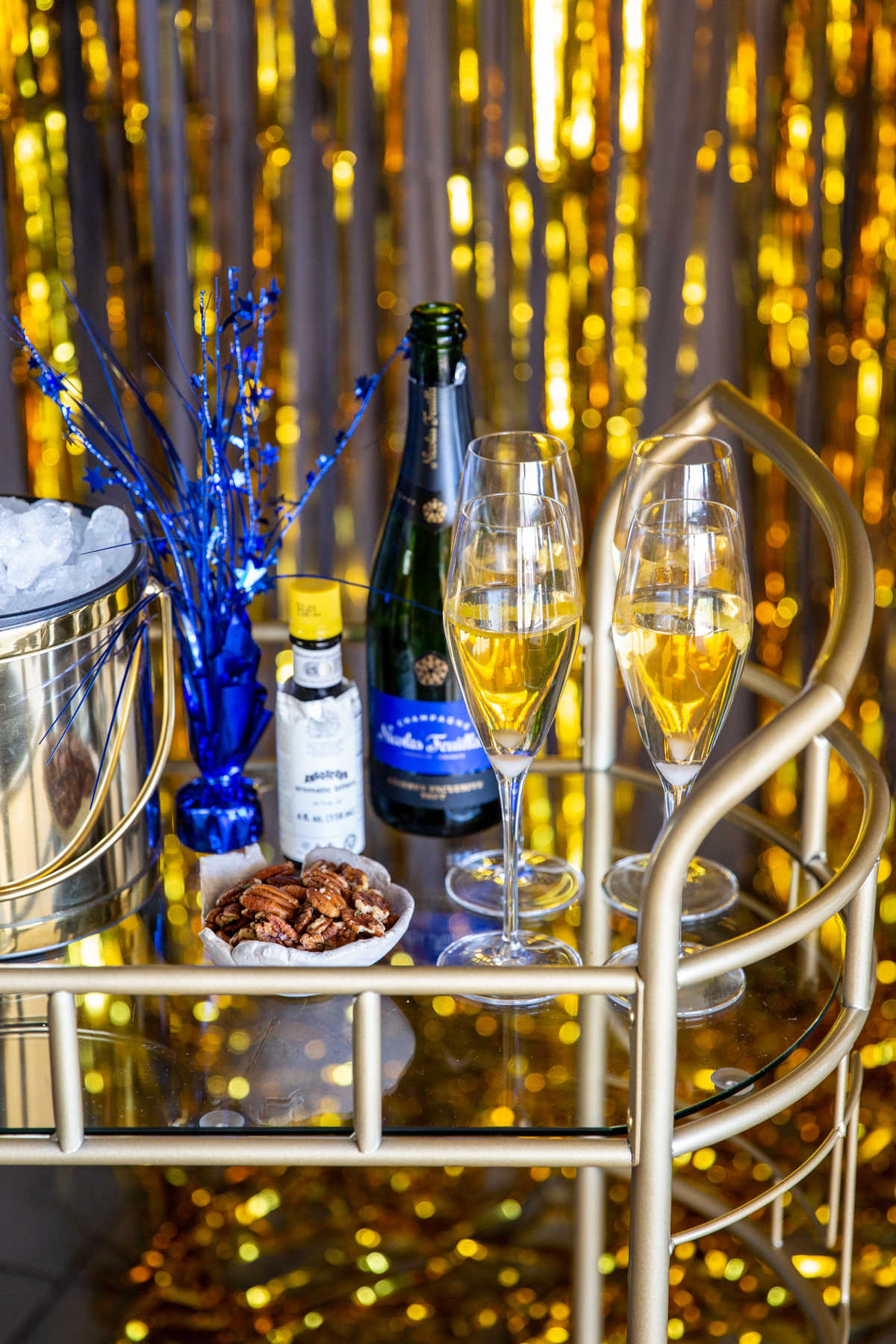 A bar cart with champagne cocktails, nuts and New Year's decorations.