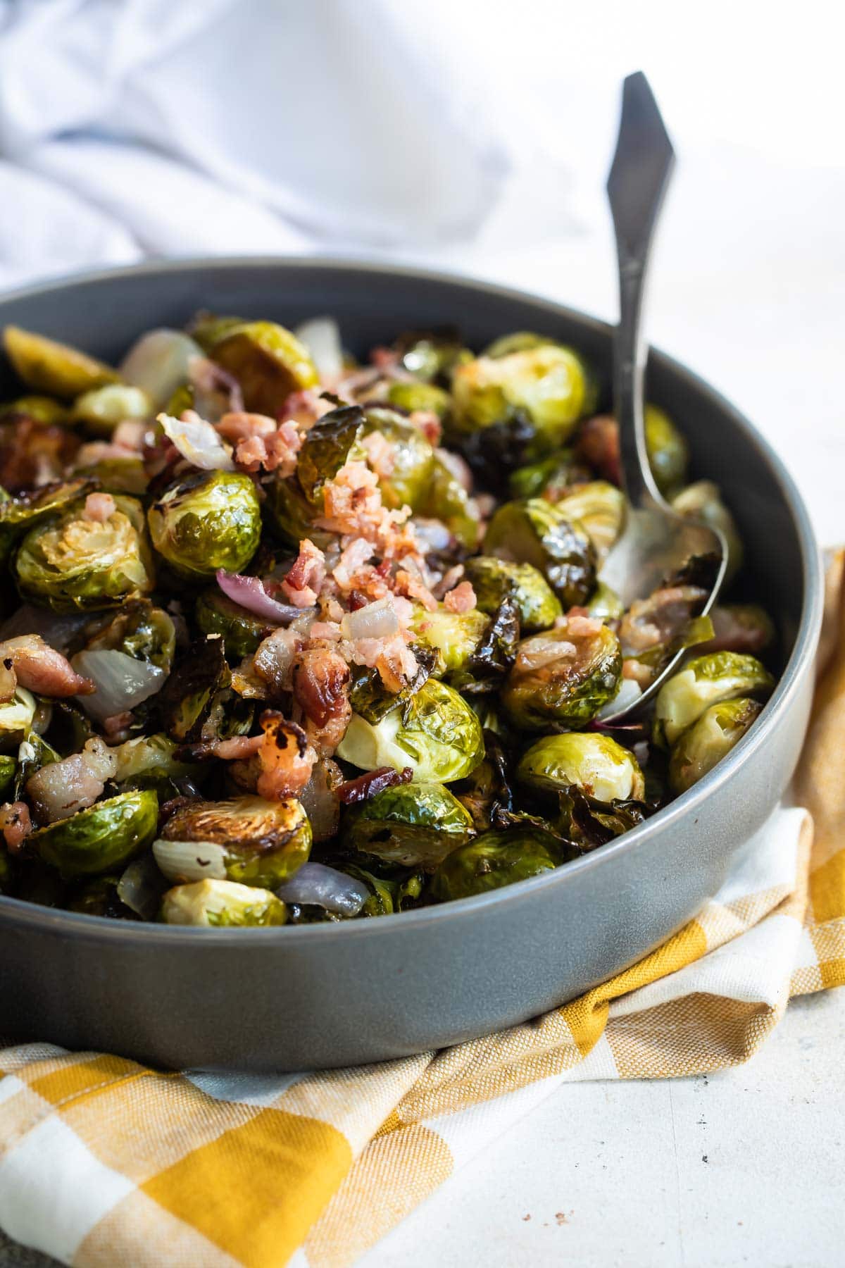 Roasted brussels sprouts being scooped out of a metal pan.