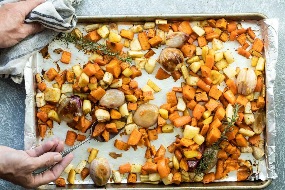 Roasted root vegetables on a parchment paper lined baking sheet.