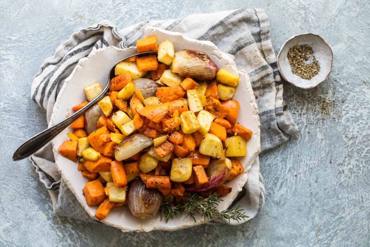 Roasted root vegetables in a white serving bowl.