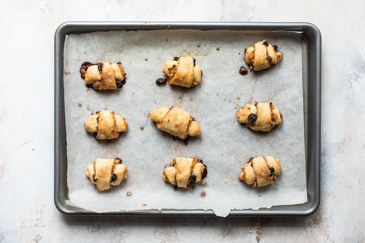 Nine baked rugelach on a parchment paper lined baking sheet.