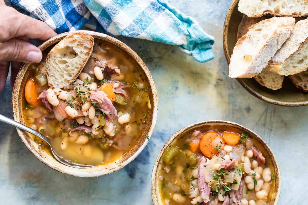 Two bowls of ham and bean soup on a table.