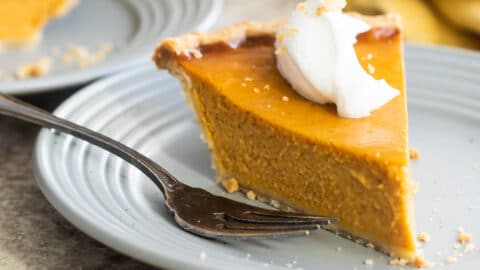 A slice of pumpkin pie on a gray plate.