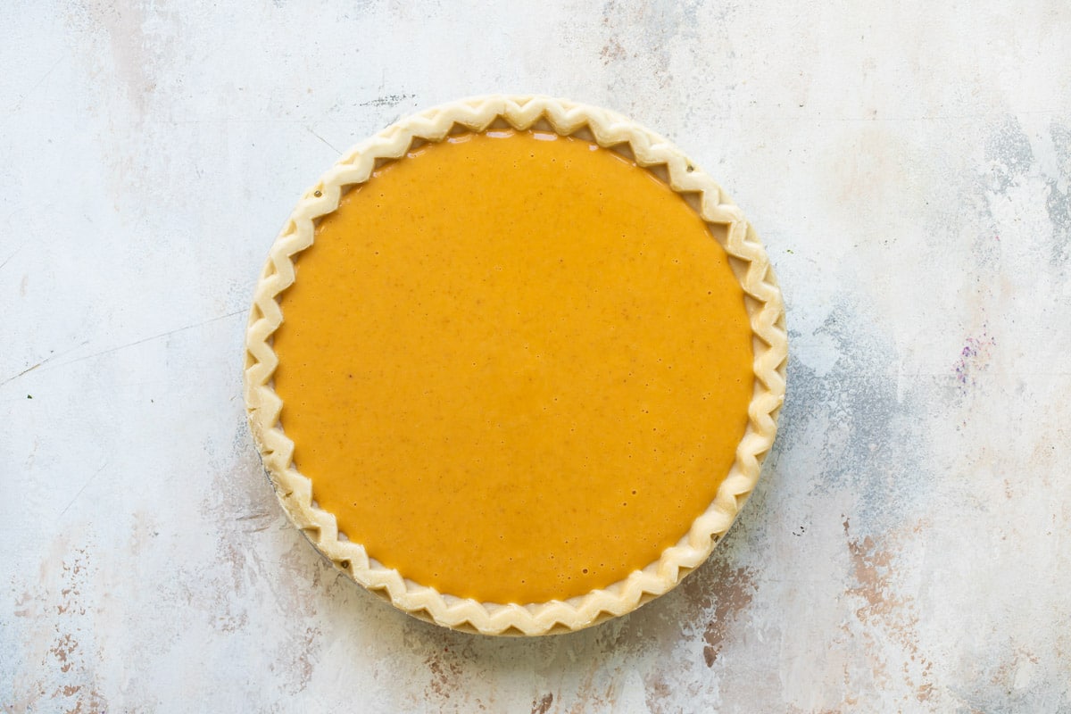 Pumpkin pie filling poured into an unbaked pie shell.