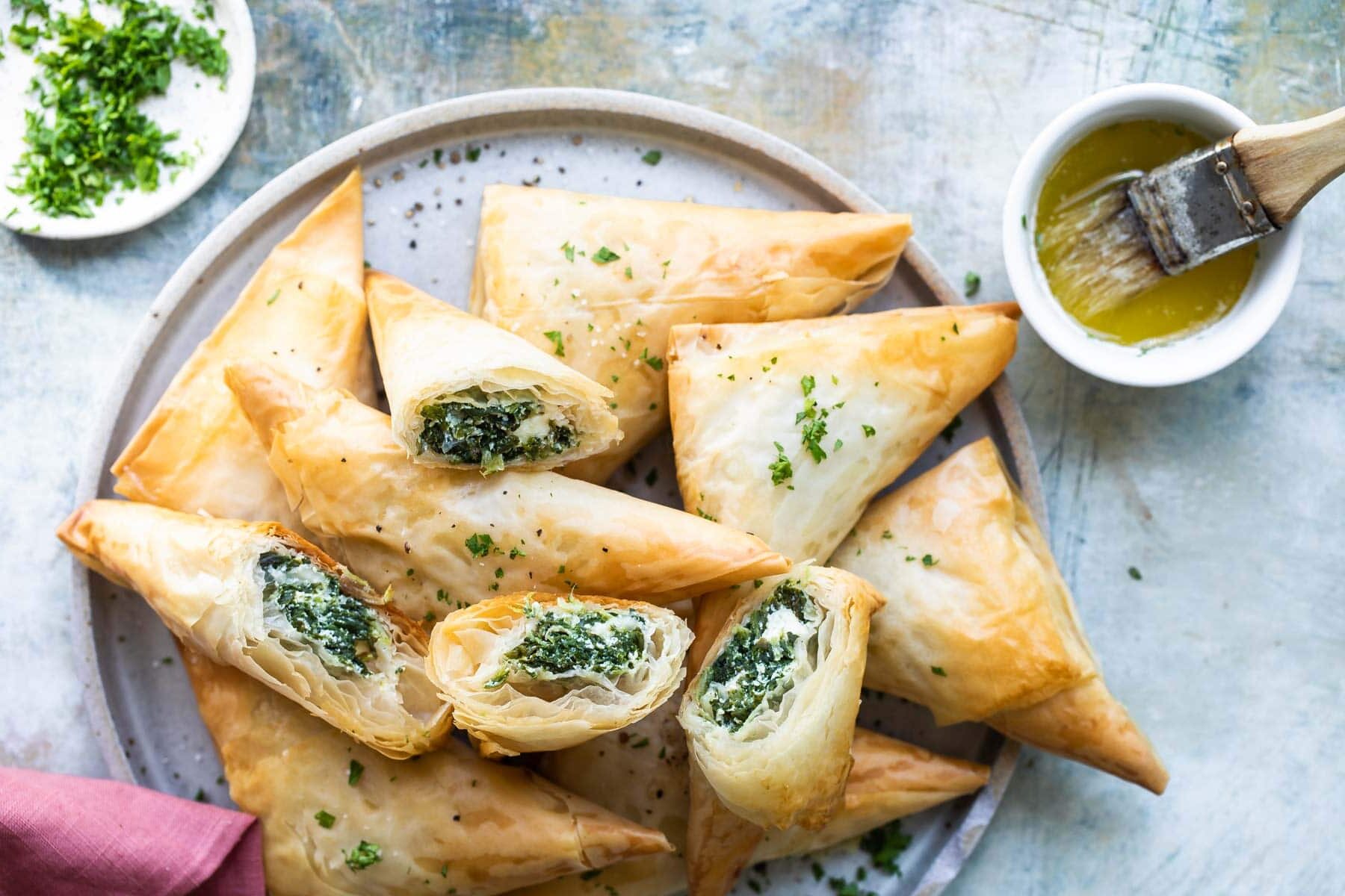 A pile of three cheese spanakopita triangles on a plate.