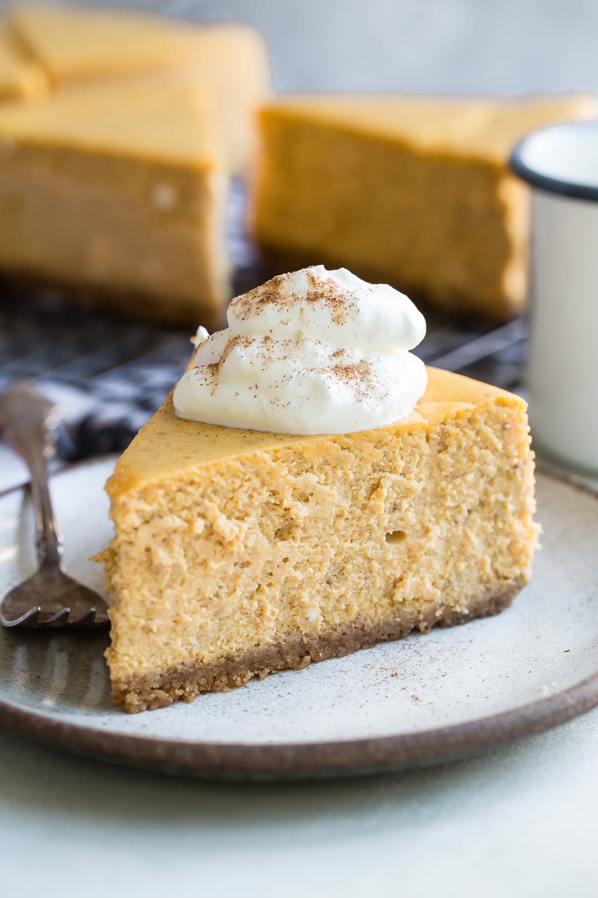 A slice of pumpkin cheesecake with whipped cream on a plate.