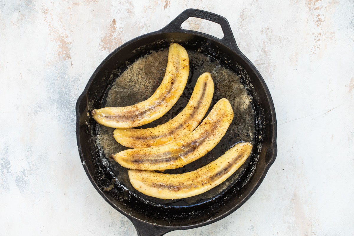 Cooked bananas sliced lengthwise in a skillet.