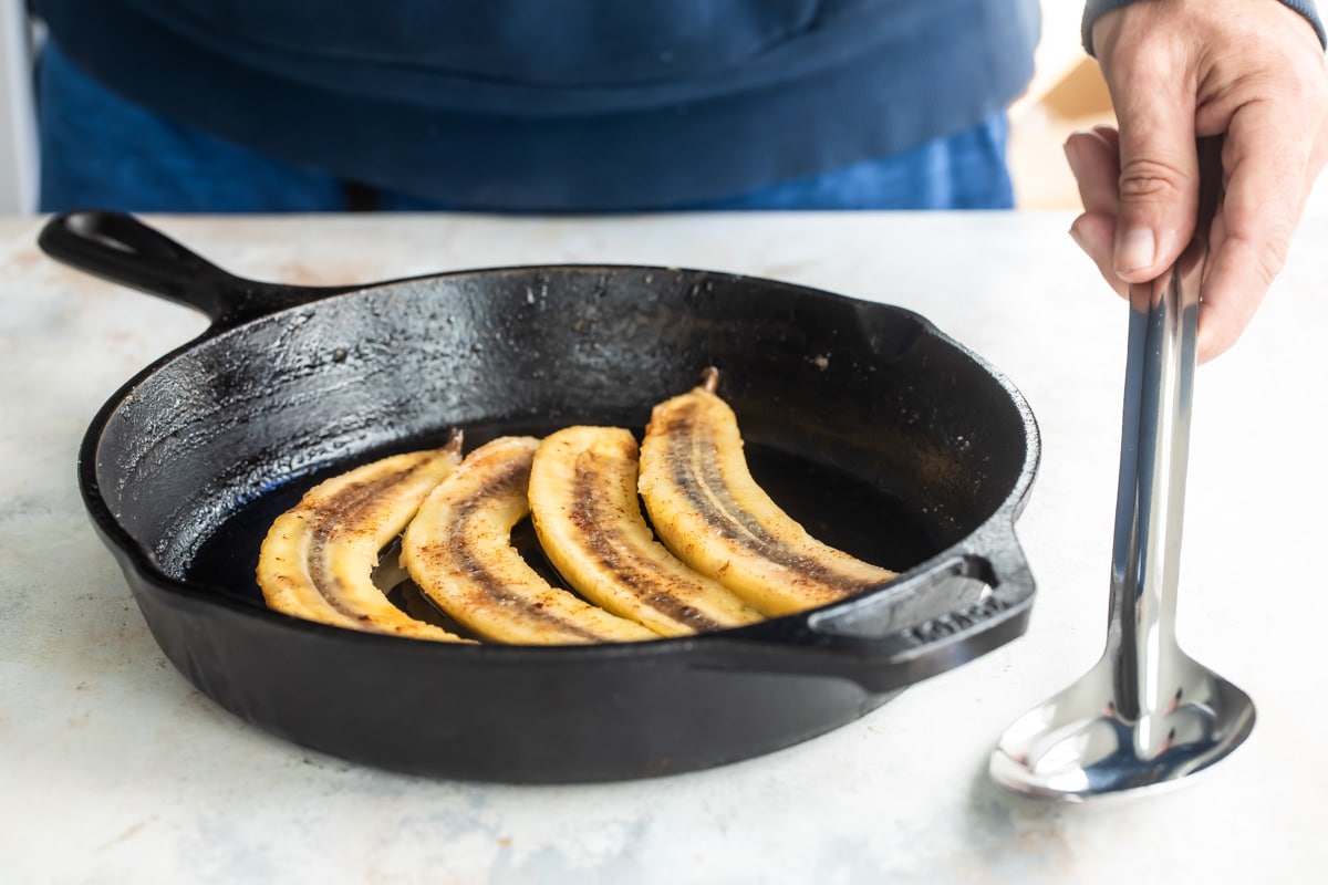 Cooked bananas sliced lengthwise in a skillet.