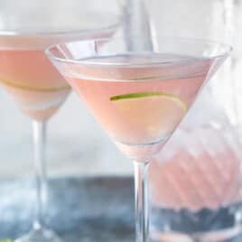 Two cosmopolitan cocktails on a galvanized metal serving tray.