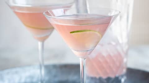 Two cosmopolitan cocktails on a galvanized metal serving tray.