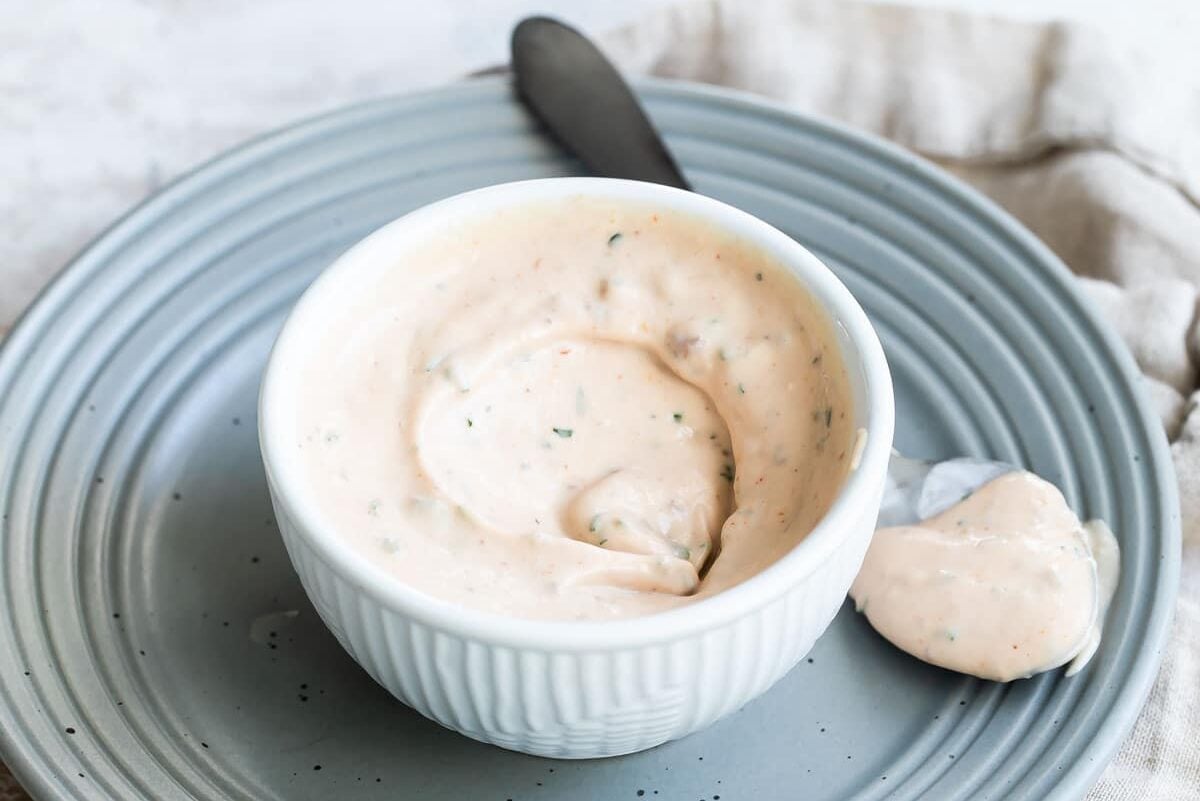 A bowl of remoulade sauce on a blue plate.