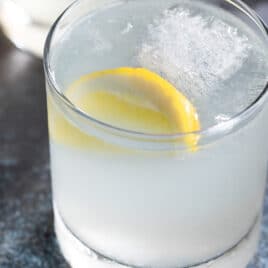 A gin fizz cocktail in glass with a lemon.