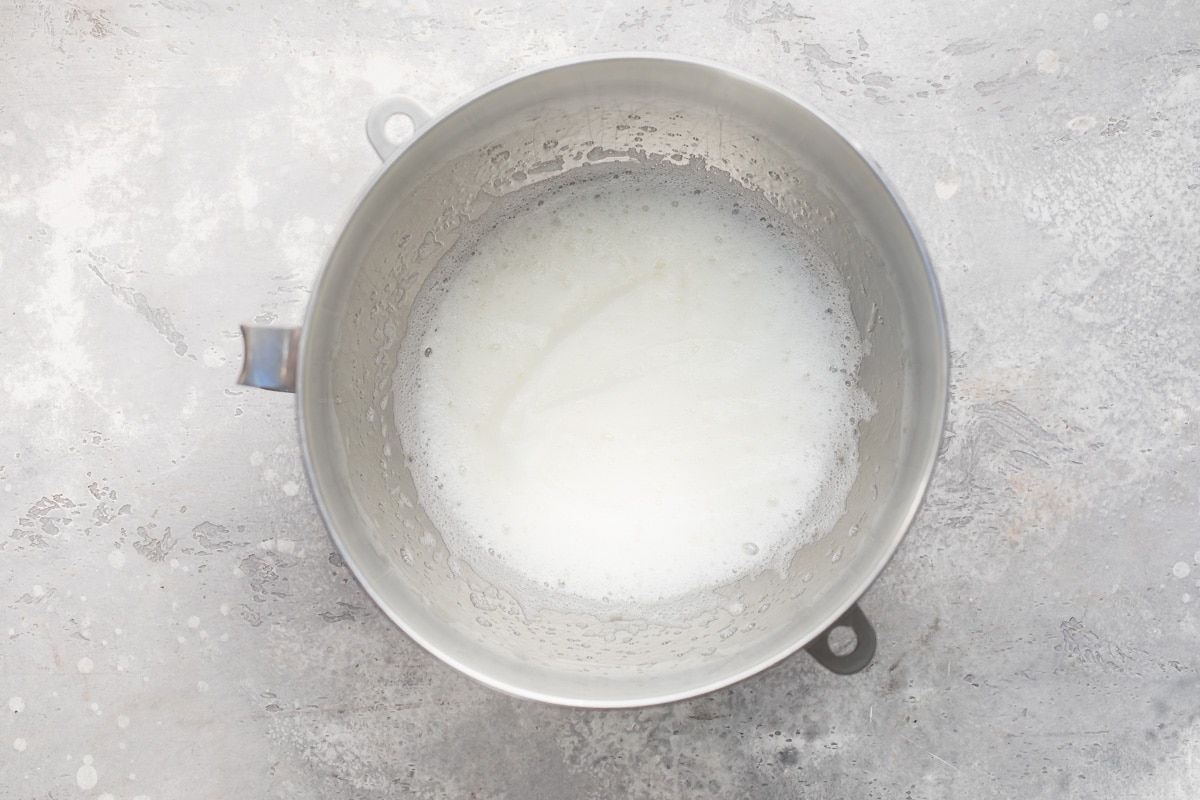 Royal icing being made in a silver mixing bowl.