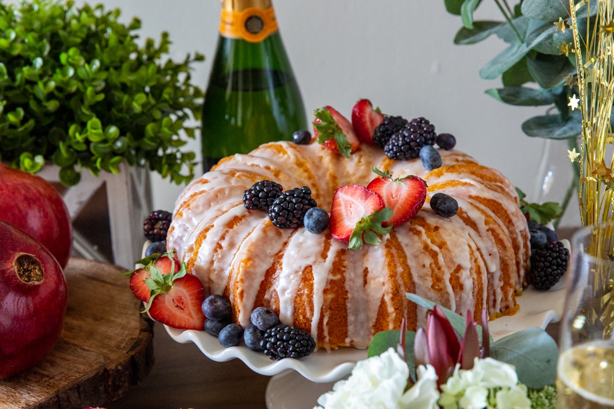A lemon bundt cake on a platter garnished with fresh berries.