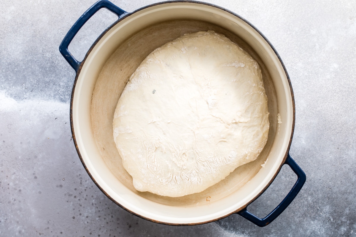 Unbaked no knead bread in a blue pot.