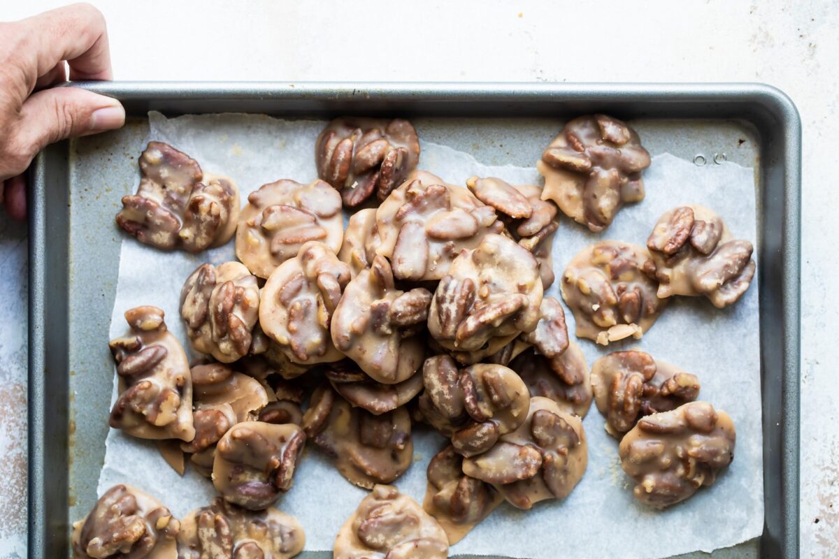 A stack of pecan pralines on a parchment paper lined baking sheet.