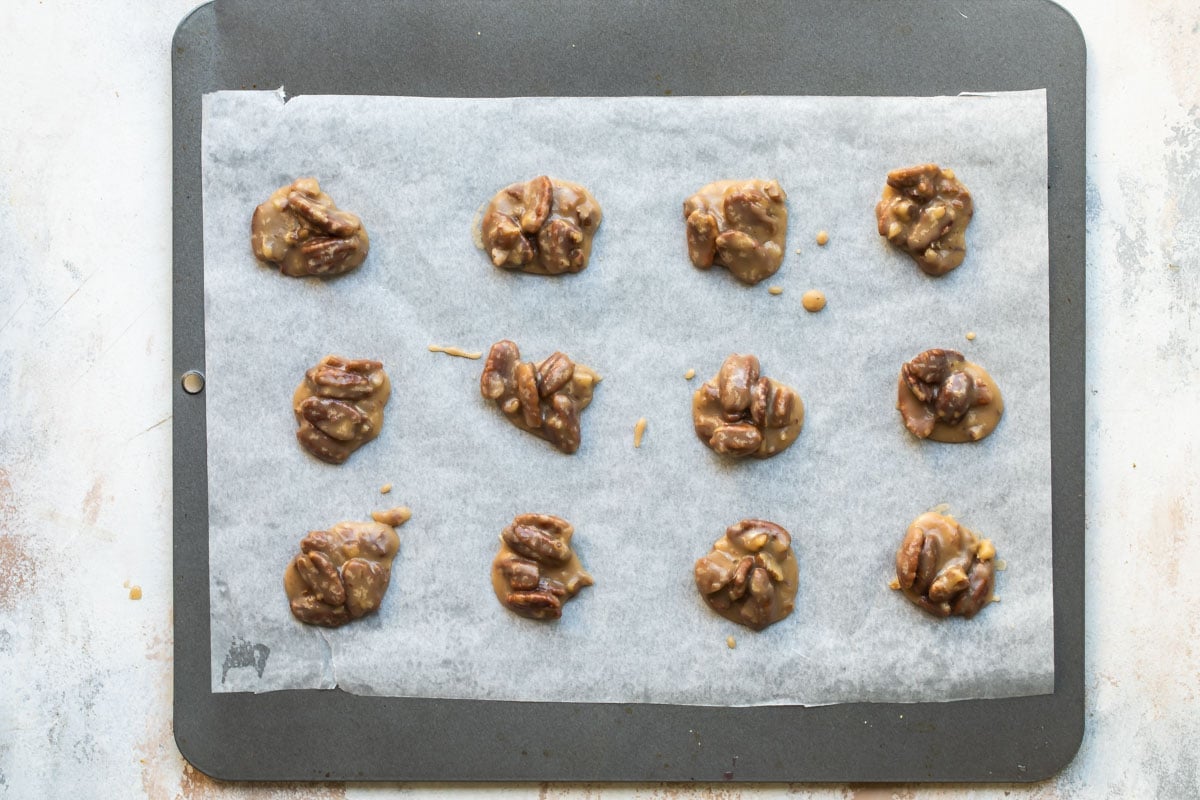 Pecan pralines on a parchment paper lined baking sheeet.