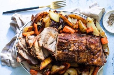 Pork roast on a plate with vegetables.