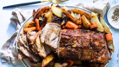 Pork roast on a plate with vegetables.