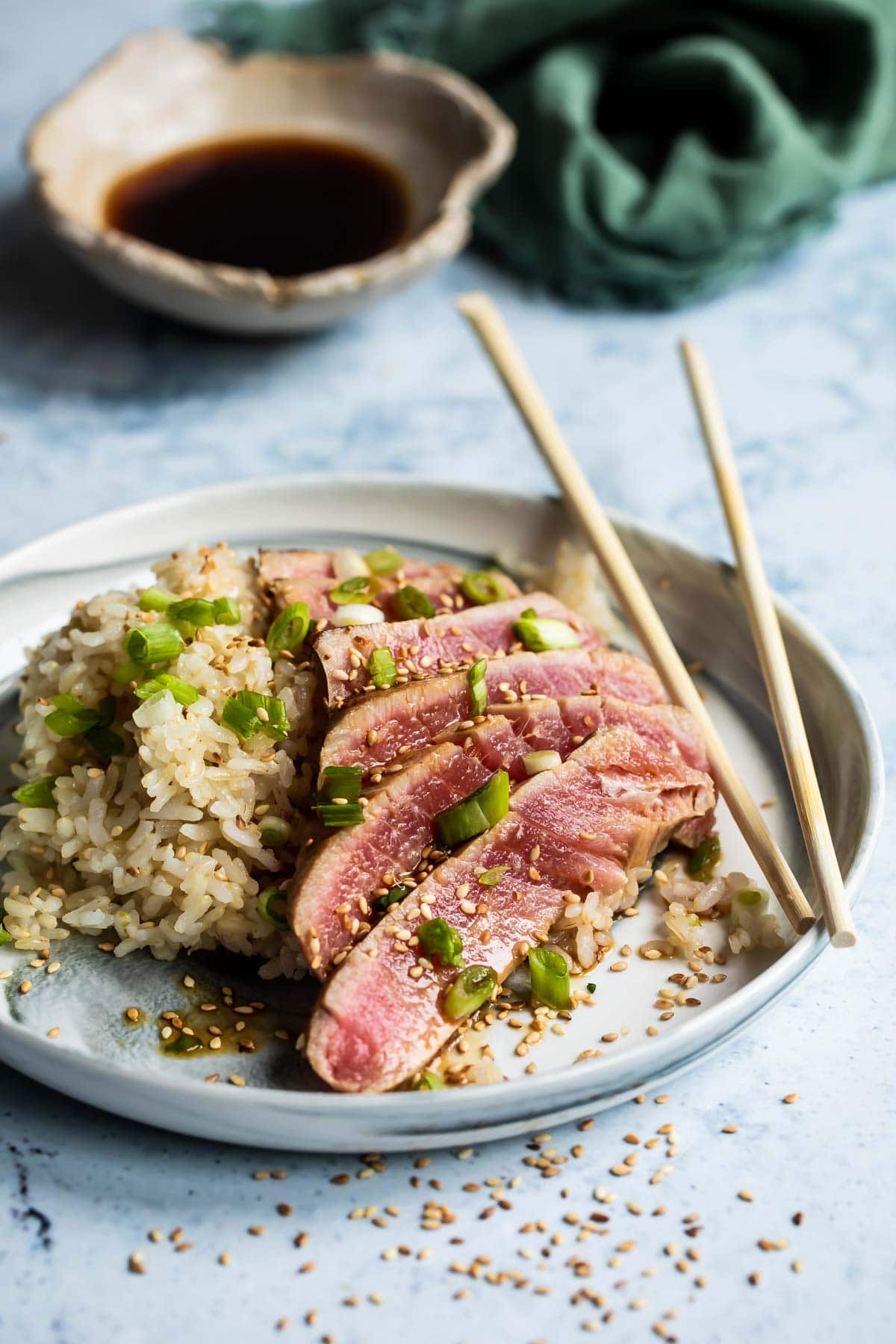 Ahi tuna on a small gray plate with rice and chopsticks.