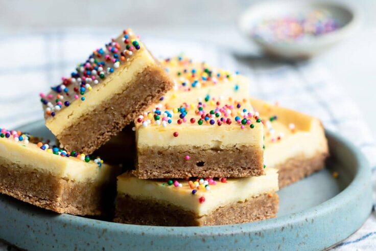 Sugar cookie cheesecake squares on a small blue plate.