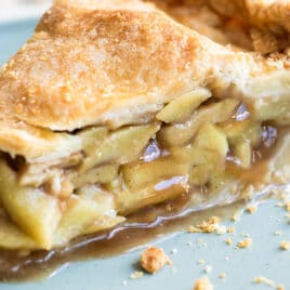 A slice of apple pie on a light blue plate.