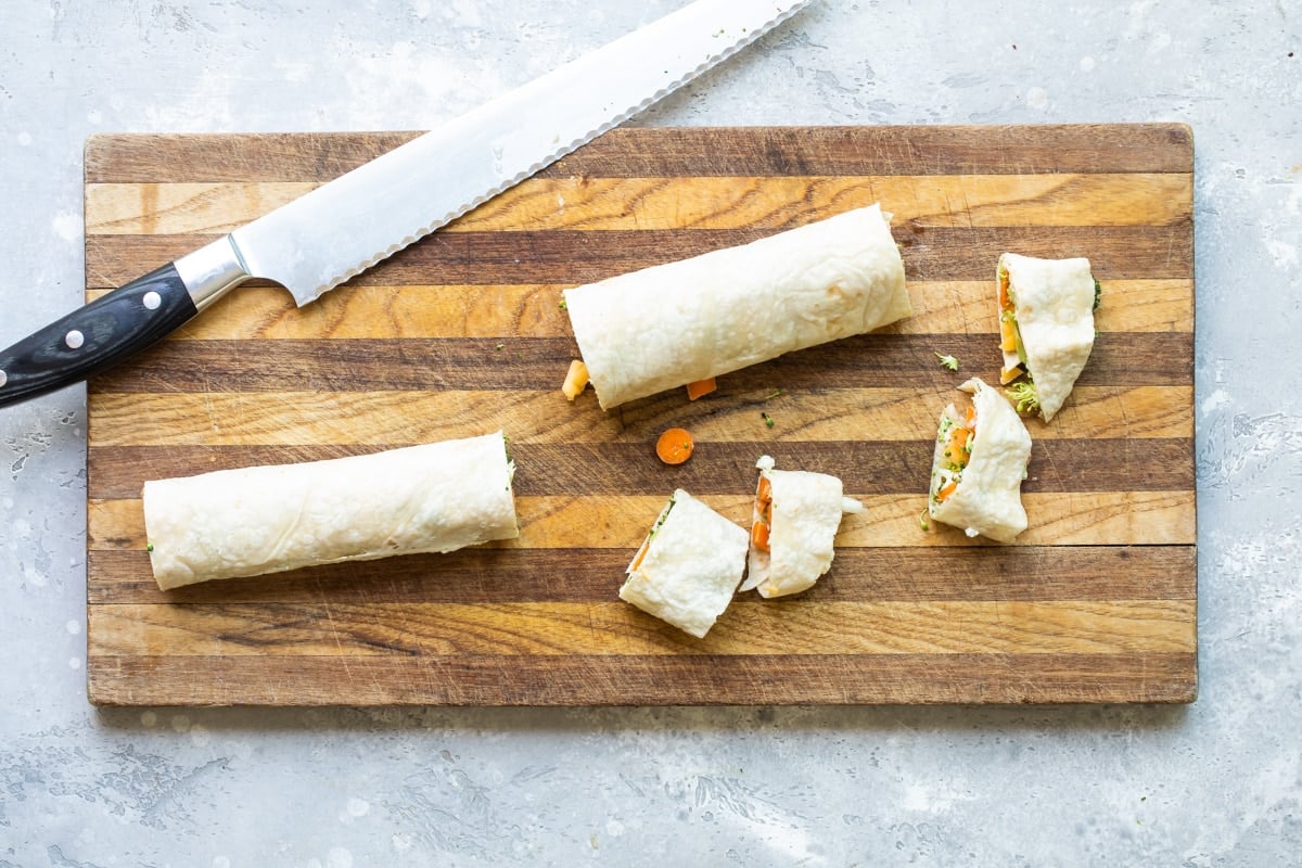 A vegetable tortilla roll up on a cutting board.