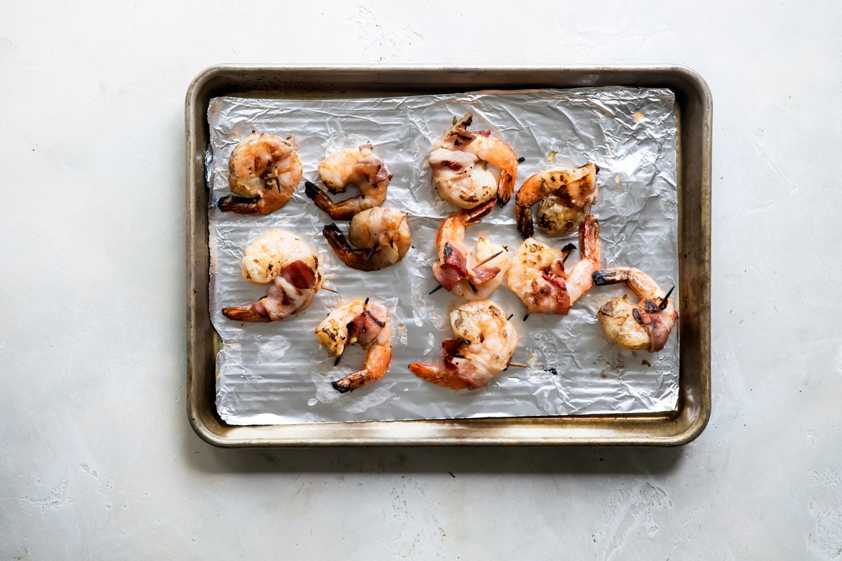 Bacon wrapped shrimp on a baking sheet.