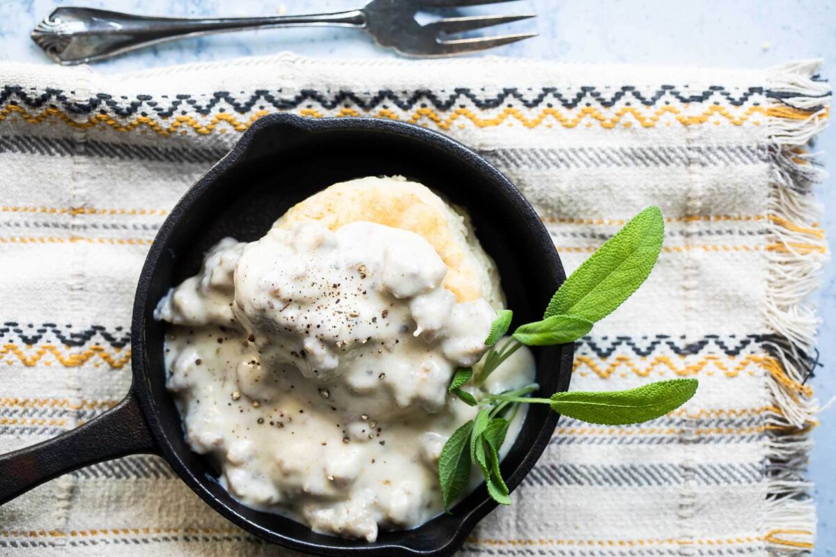 A skillet with biscuits and gravy in it.