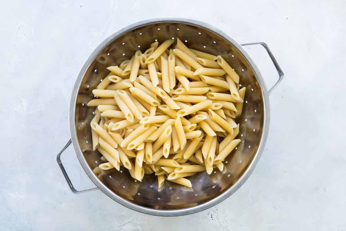 Cooked penne pasta in a colander.