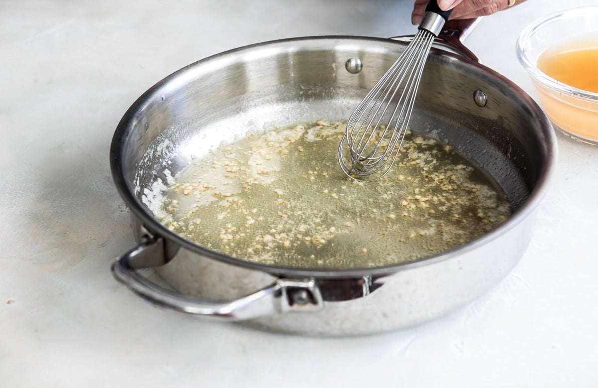 Cooking garlic in melted butter in a pan.