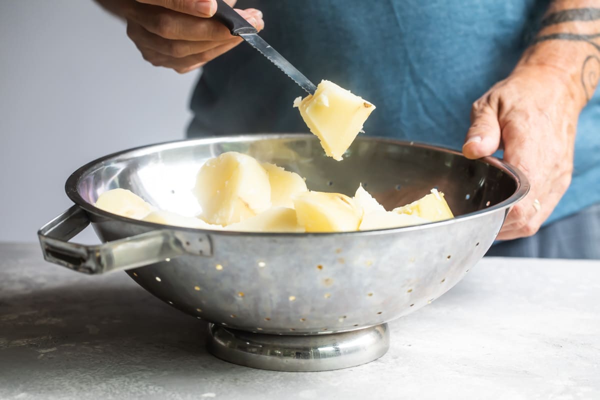 Fork-tender potato cubes in a colander after boiling.