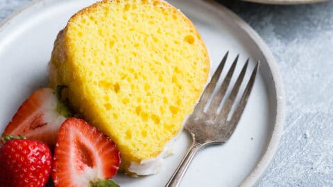 A slice of lemon bundt cake on a white plate with strawberries.