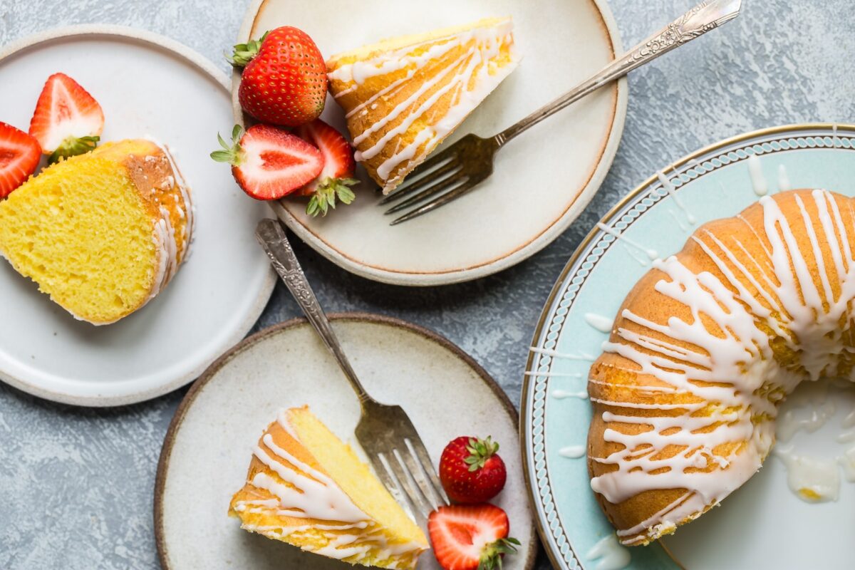 Lemon bundt cake slices on white plates with strawberries.