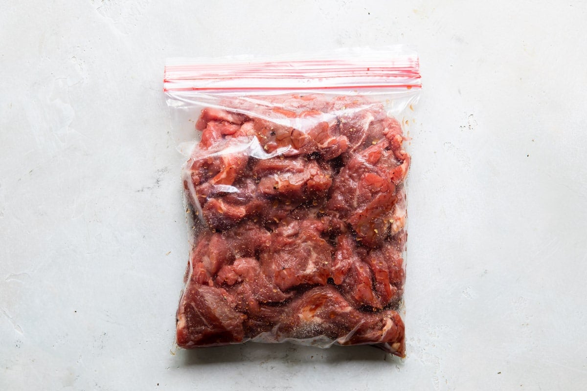 Steak marinating in a plastic bag.