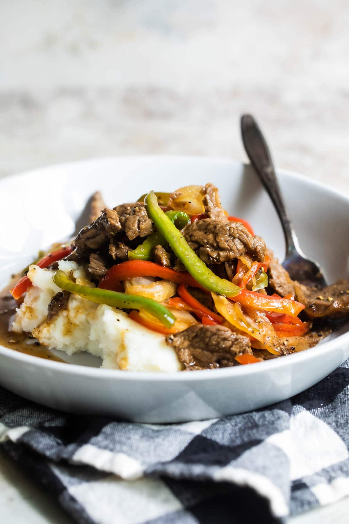 A bowl of Midwest Pepper Steak over mashed potatoes.