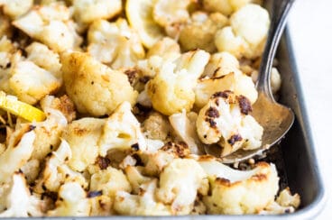 Roasted cauliflower with lemon and parmesan on a baking sheet.