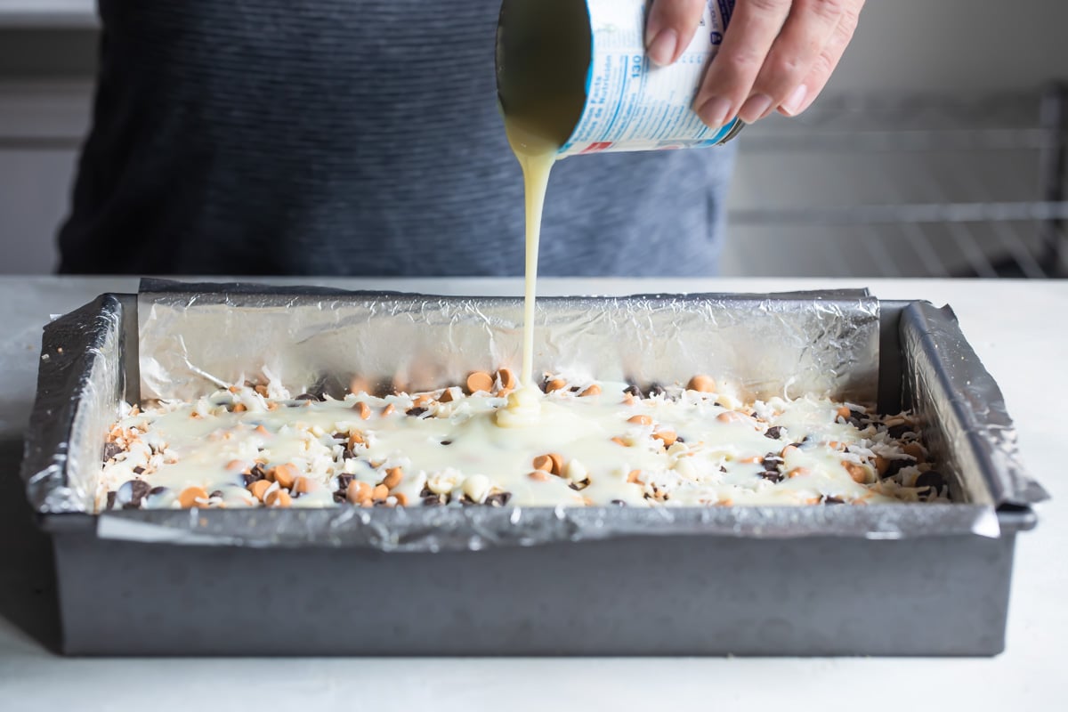 Someone pouring sweetened condensed milk into a baking pan.