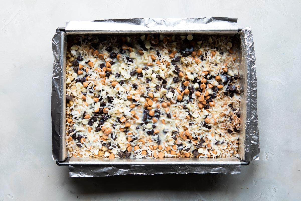 Seven layer bars squares in a baking pan before being baked.