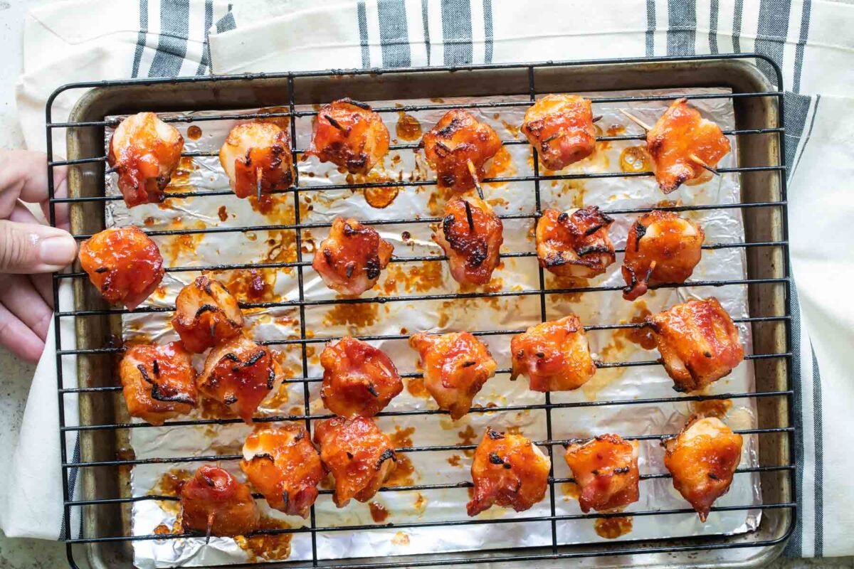 Bacon wrapped water chestnuts with barbecue sauce on a baking rack after being baked.