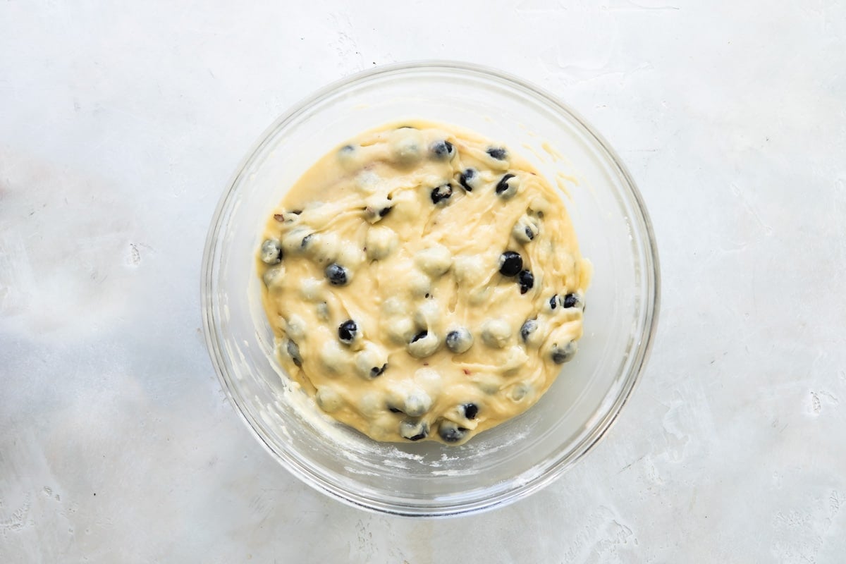 Blueberry muffin batter in a clear bowl.