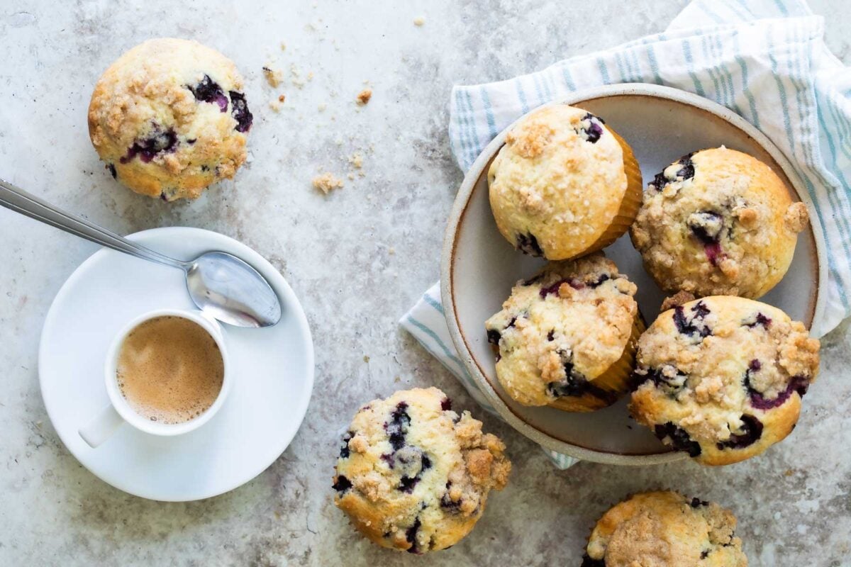 Blueberry muffins in a bowl on a counter next to a cup of espresso.
