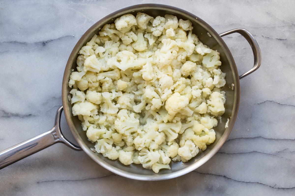 A skillet with cauliflower in it.