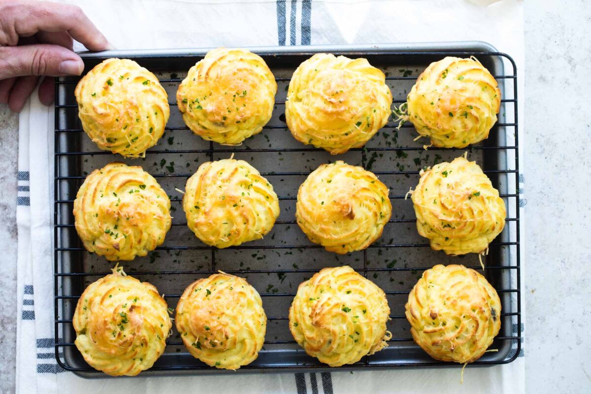 A baking rack with Duchess potatoes on top.