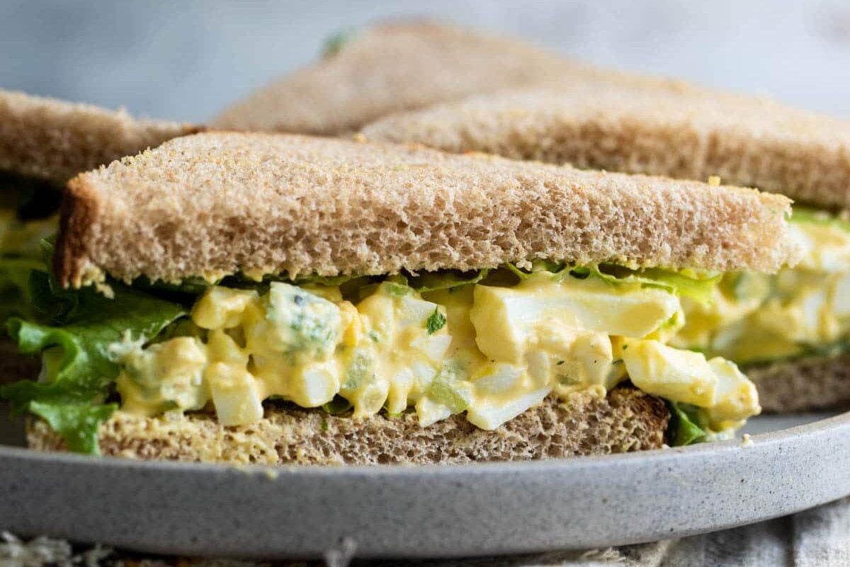 Egg salad sandwiches on a gray plate.