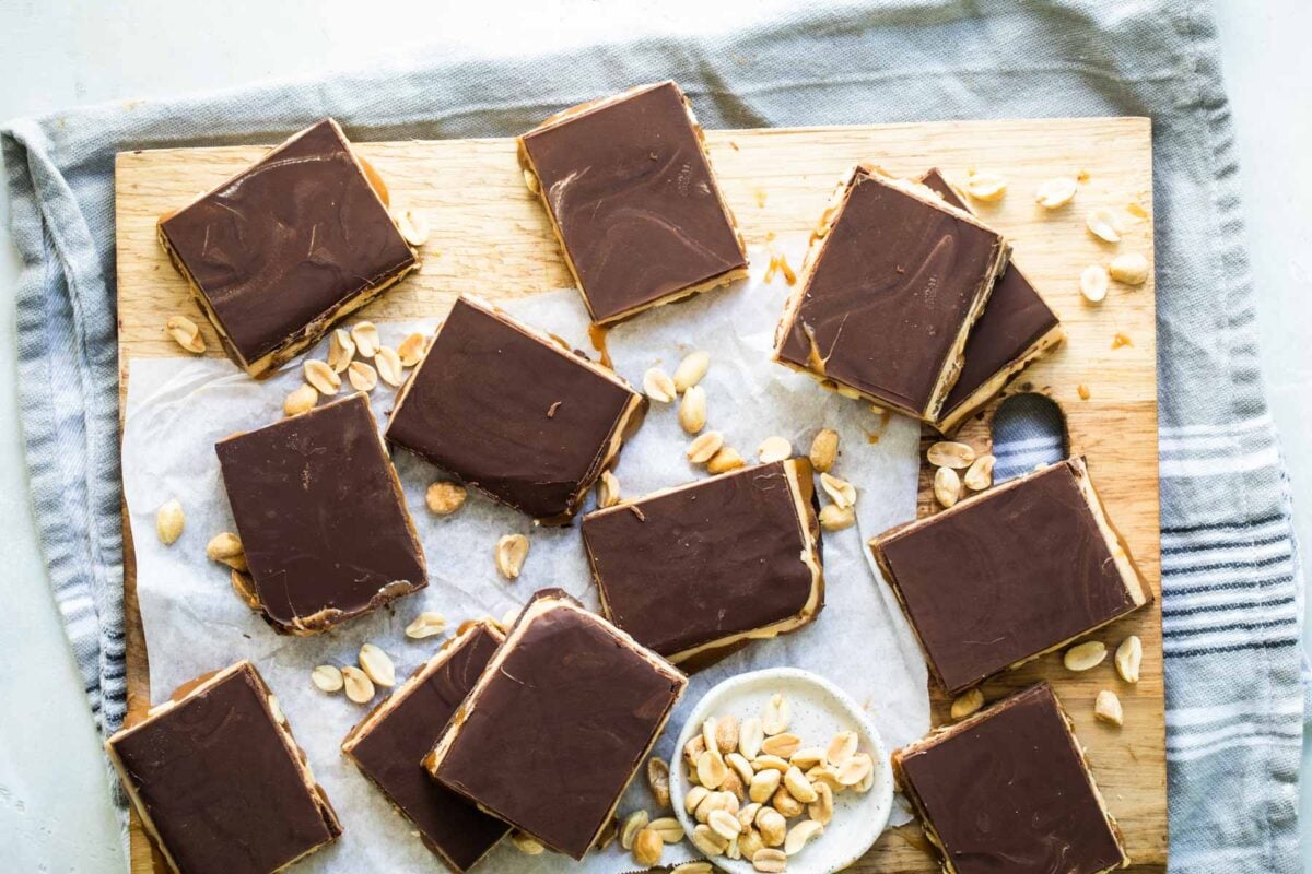 Homemade Snickers bars on a wooden cutting board.